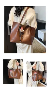 Detail of dark brown leather tote bag with cute lamb plush charm and striped ribbon