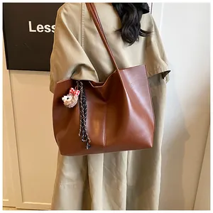 Detail view of large brown faux leather tote bag with cute alpaca charm and tassel