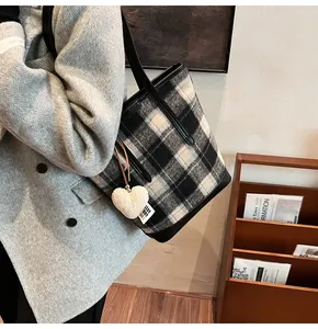 Detail of checkered wool tote bag with heart charm shown on grey coat outfit