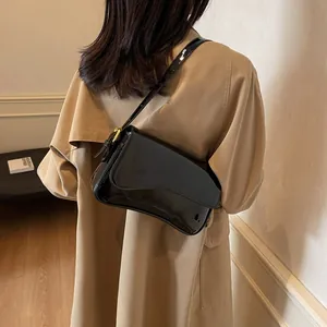 Glossy black patent leather shoulder bag with gold buckle and adjustable strap