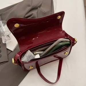 Polished burgundy patent leather baguette bag interior with golden magnetic buckles