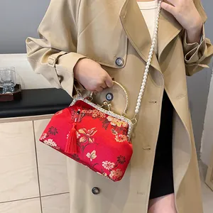 Sac brodé chinois rouge avec motifs floraux dorés et bandoulière en chaîne de perles