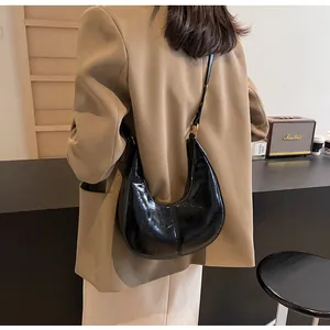 Detail of a black shiny pleated leather hobo bag with sleek metal ring hardware