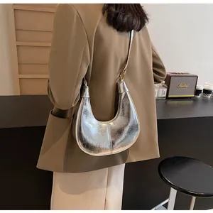 Silver metallic dumpling bag with vintage texture worn on shoulder with light blazer