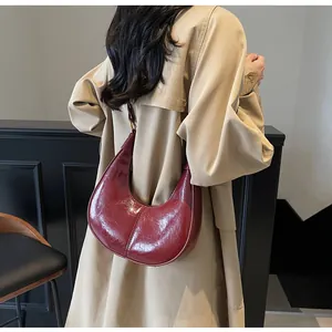 Detail view of the deep red crescent moon shoulder bag in glossy vintage faux leather texture