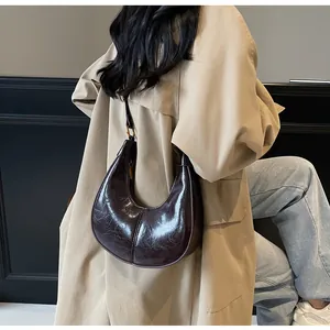 Deep brown crescent hobo bag with glossy oil wax finish and stylish pleated texture