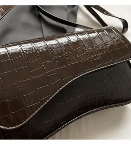 Detailansicht der dunkelbraunen Krokodil-Textur mit glänzender Lackleder-Oberfläche