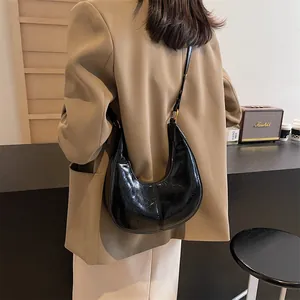 Chic black glossy wrinkled leather half-moon shoulder bag with elegant gold metal ring