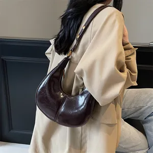 Glossy deep brown croissant shoulder bag in crescent shape with gold metal buckle detail