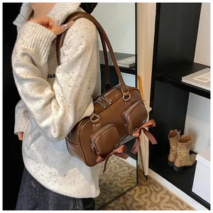 Detail of dark brown shoulder bag with metal zippers and satin bow decorations