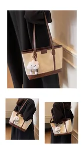 Détail d'un sac cabas bicolore en toile et cuir marron avec un pendentif nuage