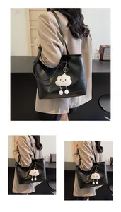 Détail d'un cabas noir en similicuir avec un charm nuage en peluche blanche et bandoulière