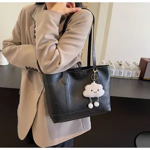 Détail d'un sac cabas noir en similicuir avec un pendentif nuage en peluche blanche