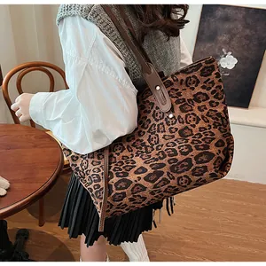 Détail du grand sac cabas à motif léopard avec des poignées en cuir marron et rivets