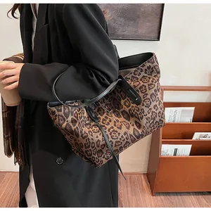 Détail du sac cabas imprimé léopard avec anses en cuir noir porté à l'épaule