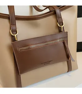 Detail der beigen Shopper-Tasche mit Lederstruktur und dunkelbraunem Griff mit goldener Schnalle