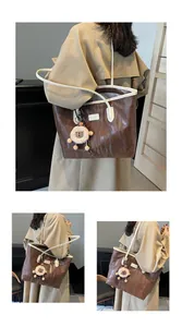 Detail of dark brown tote bag with embossed animal texture and plush sheep charm