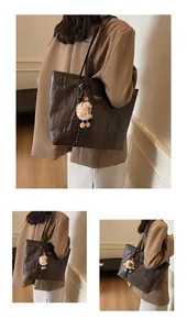 Macro shot of dark brown tote bag with zebra texture, long straps, and a plush lamb charm