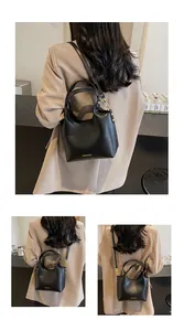 Détail du sac seau en cuir noir avec logo doré et poignées métalliques circulaires