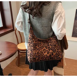 Detail of leopard print tote bag with brown leather strap in a warm cafe setting
