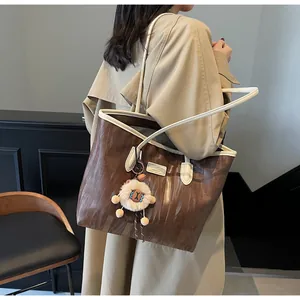 Detail of a large brown tote bag with wood-grain texture and cute sheep charm