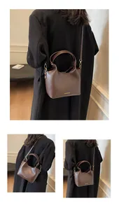 Détail d'un sac seau marron vintage avec texte doré et conception à double bandoulière
