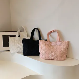 Borse tote trapuntate nei colori nero, bianco e rosa su un supporto da esposizione