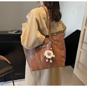 Brown vintage tote bag with plush charm shown on model in khaki coat, large capacity