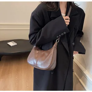 Brown oil wax leather shoulder bag with a vintage crescent shape and gold hardware