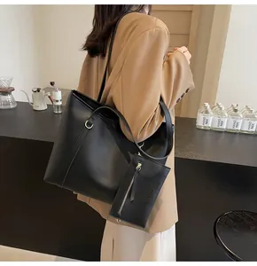Detalle del bolso tote negro en piel sintética con estuche a juego y detalle de aro de metal