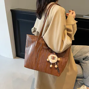 Brown zebra-patterned tote bag with double shoulder straps and a plush sheep pendant