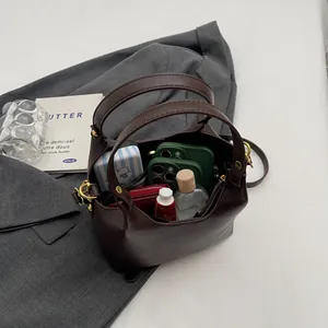 Sac fourre-tout rétro en cuir mat marron foncé avec détails dorés sur un blazer gris