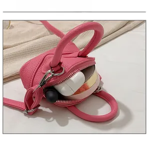 Makroansicht der Kapazität für Lippenstift und Ohrhörer in der rosa Mini-Umhängetasche