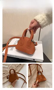Detail einer braunen Mini-Muschel-Umhängetasche mit Litchi-Struktur und Handgriffen