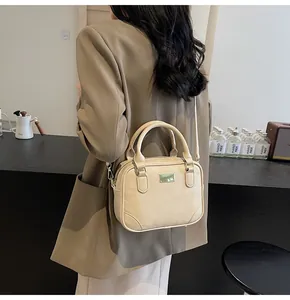 Detail of a beige matte PU leather handbag with dual handles and golden metal plaque