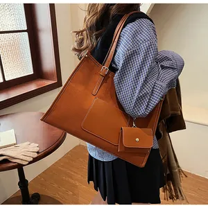 Detail of a large brown tote bag featuring adjustable metal buckles and a mini coin pouch