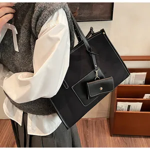 Detail of a large black matte leather tote bag featuring contrast stitching and a mini pouch