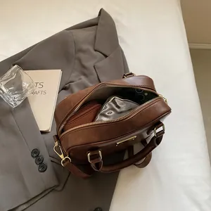 Vintage brown leather crossbody bag shown on bed with blazer for professional work style
