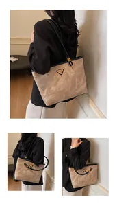 Close-up of a vintage-textured tote bag showing the metallic triangle logo and slim straps