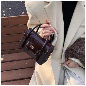 Detail shot of vintage coffee-brown leather handbag with gold logo and contrast flap
