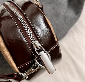 Close-up of premium silver metal zipper and dark brown glossy leather texture on bowling bag