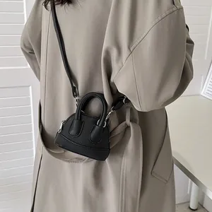 Mini-Umhängetasche aus schwarzem Leder mit silbernen Akzenten auf einem Mantel