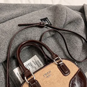 Detail of contrast stitch shoulder strap and beige canvas leather patchwork bowling bag