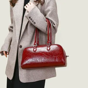 Sac bowling en cuir verni rouge avec double poignée porté avec un blazer en laine