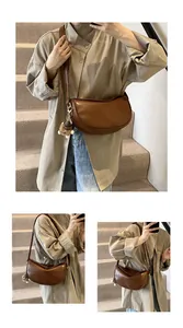 Detail of brown PU leather half-moon crossbody bag with adjustable strap and fluffy pendant