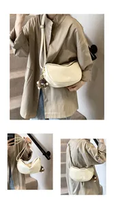 Detail of off-white crescent crossbody bag with soft PU texture and cute plush charm