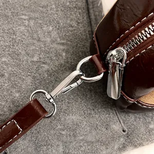 Detailed close-up of dark brown patent leather bowling bag with silver metal hooks