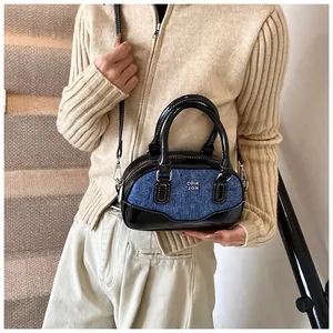 Model showing a mini bowling bag in blue denim and black shiny leather contrast