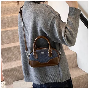 Detail of mini bowling bag with brown leather and blue denim stitching and shoulder strap