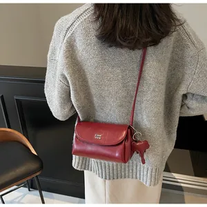Détail du sac rouge en cuir avec logo argenté et charmant pendentif éléphant
